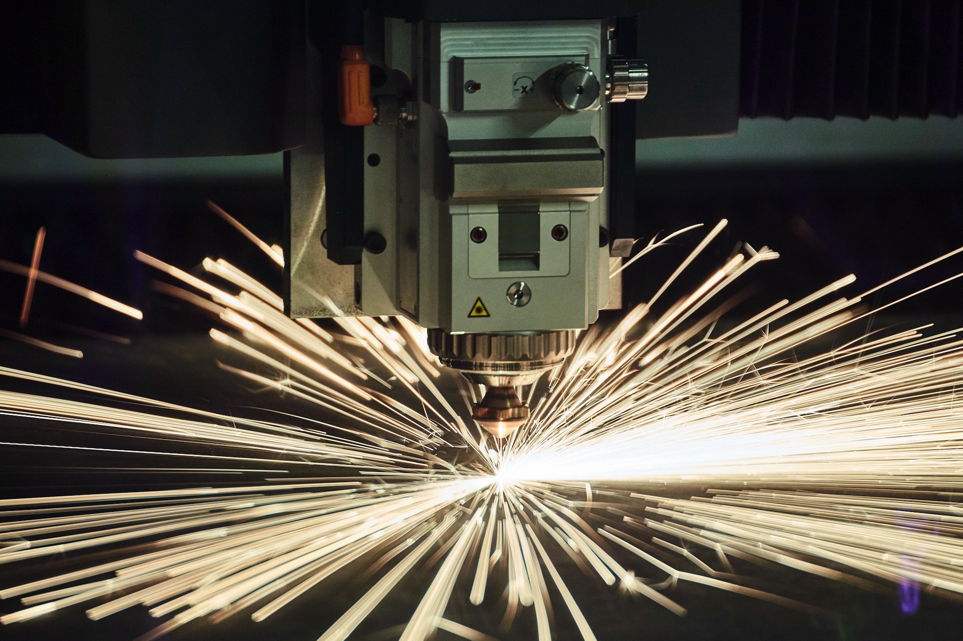 Close-up of a fiber laser cutting head during flat-sheet processing.